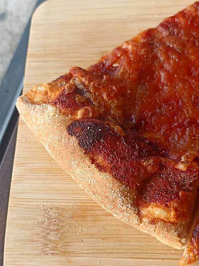 Una porción de Pizzalvi con el borde dorado sobre una tabla de bambú