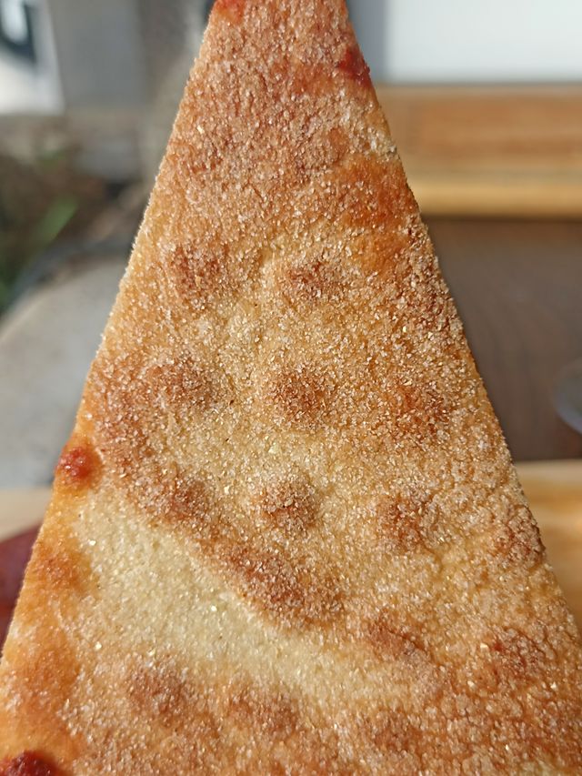 La base crujiente de una porción de Pizzalvi, vista por debajo
