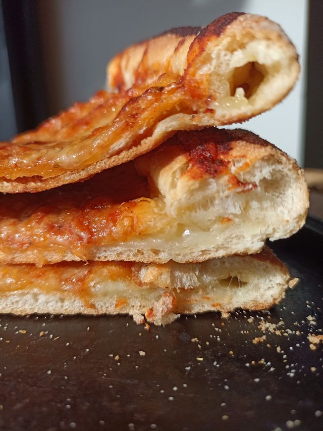 Corte lateral del borde apilado de una Pizzalvi, con el queso derretido por dentro de la masa