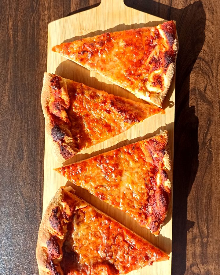 Cuatro porciones de Pizzalvi sobre una tabla de madera, vistas desde arriba